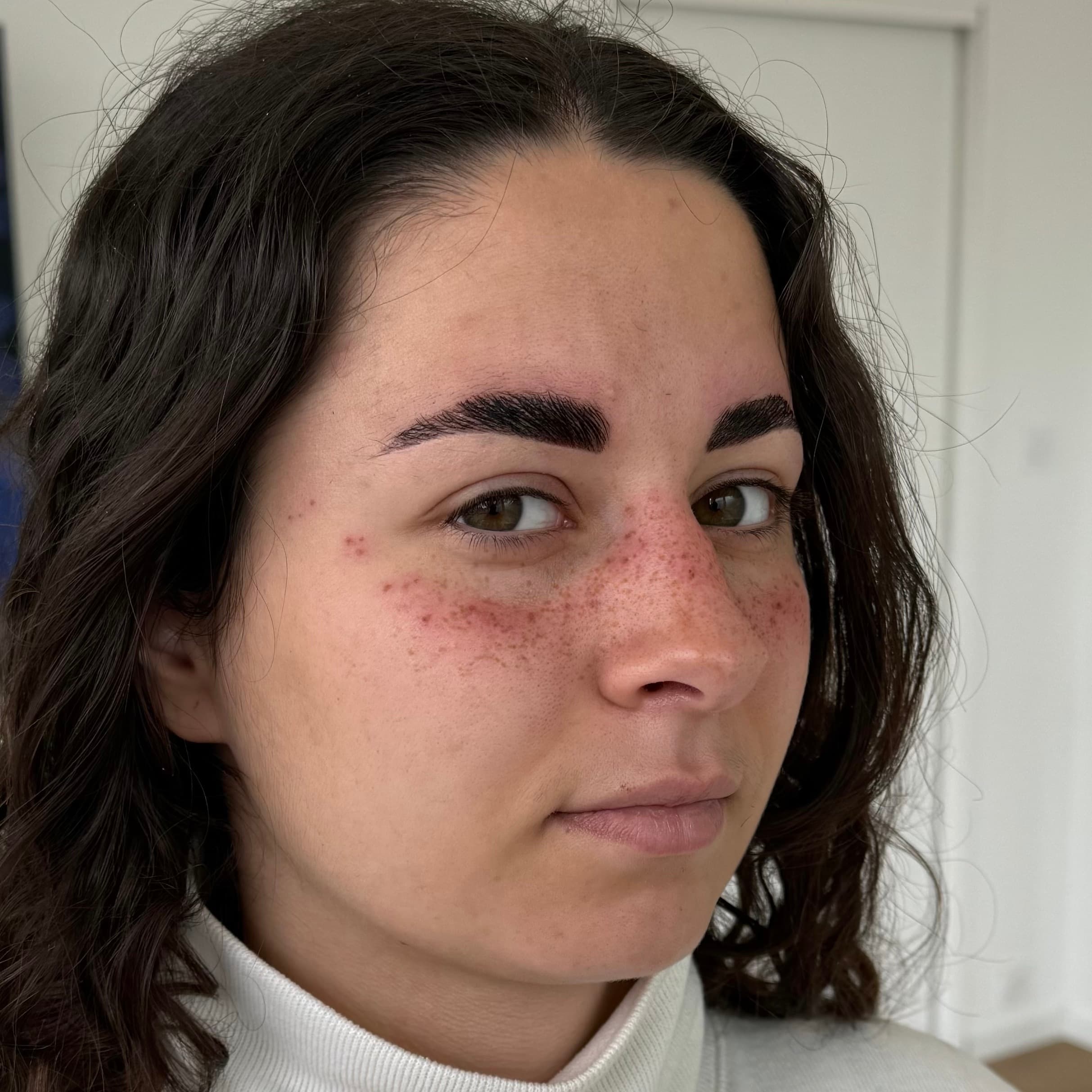 Jeune femme souriante après séance de tatouage faux freckles sur le haut des joues, maquillage semi-permanent à Dijon.